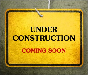 Alert yellow sign hanging by fishhook, conceptual image for under construction and coming soon